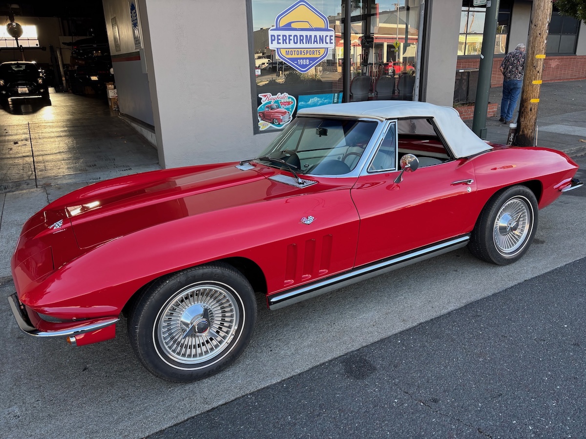 red 1965 corvette parked outside shop