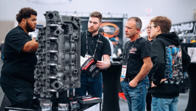 Attendees at PRI show standing next to car engine