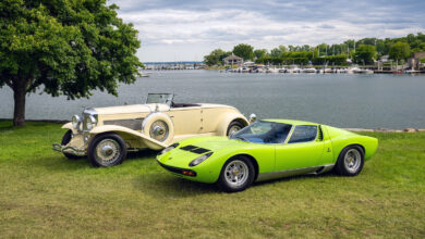 To classic cars parked next to lake.