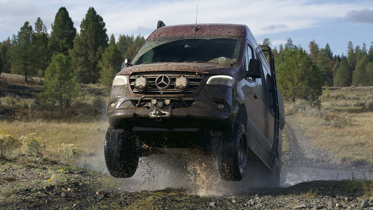 lifts & leveling kits van compass kit on a off-road sprinter van catching air over a dirt road stream crossing