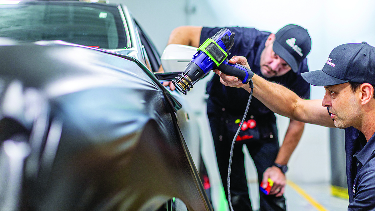 Two men applying vinyl wrap to a vehicle