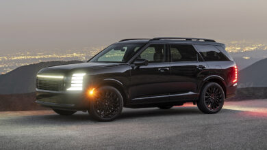 2027 Palisade Hybrid Calligraphy Black Ink Edition three-quarter front view with lights on at dusk