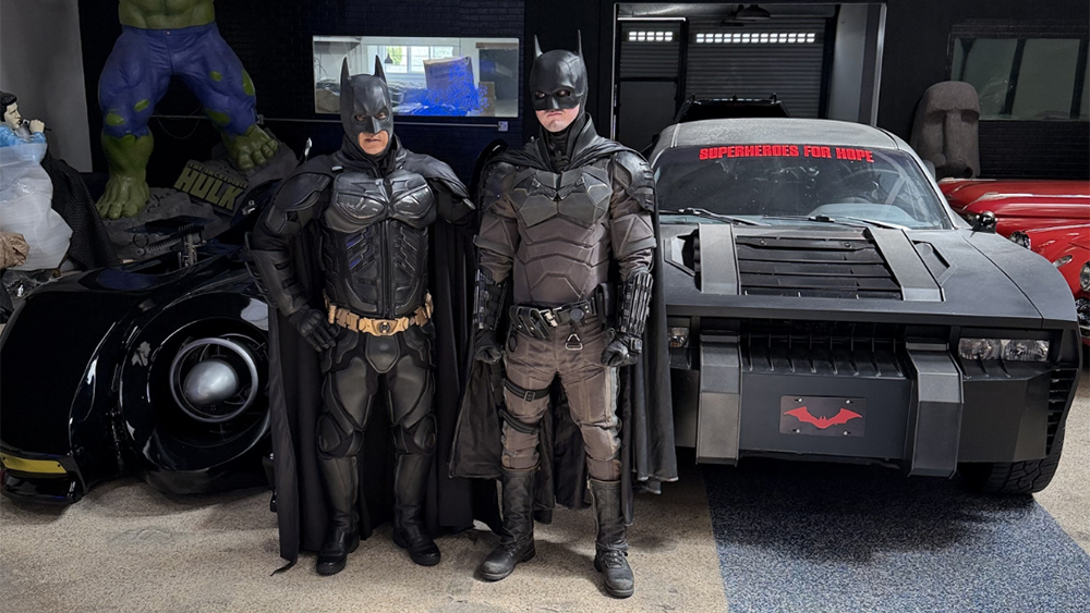 BatMentor standing in front of Batmobiles