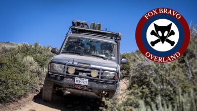 Defender on dirt trail with Fox Bravo Overland logo