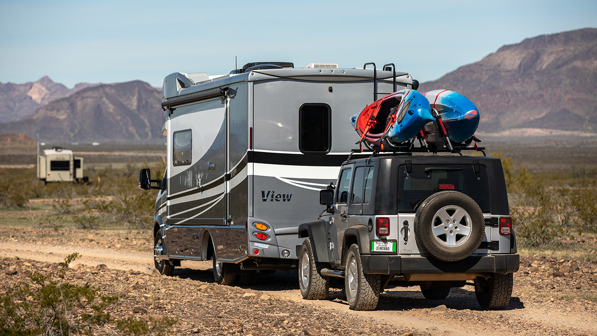 RV towing Jeep on dirt road