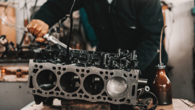 Auto mechanic adjusting cylinder head on engine block with wrench at workshop.