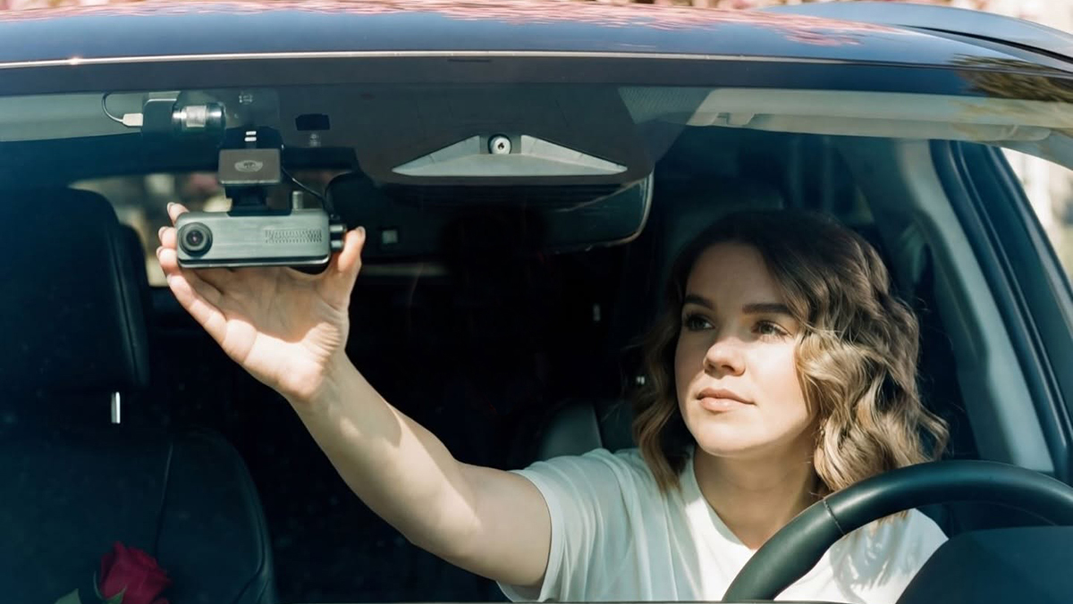 Woman adjusting dash cam from driver's seat
