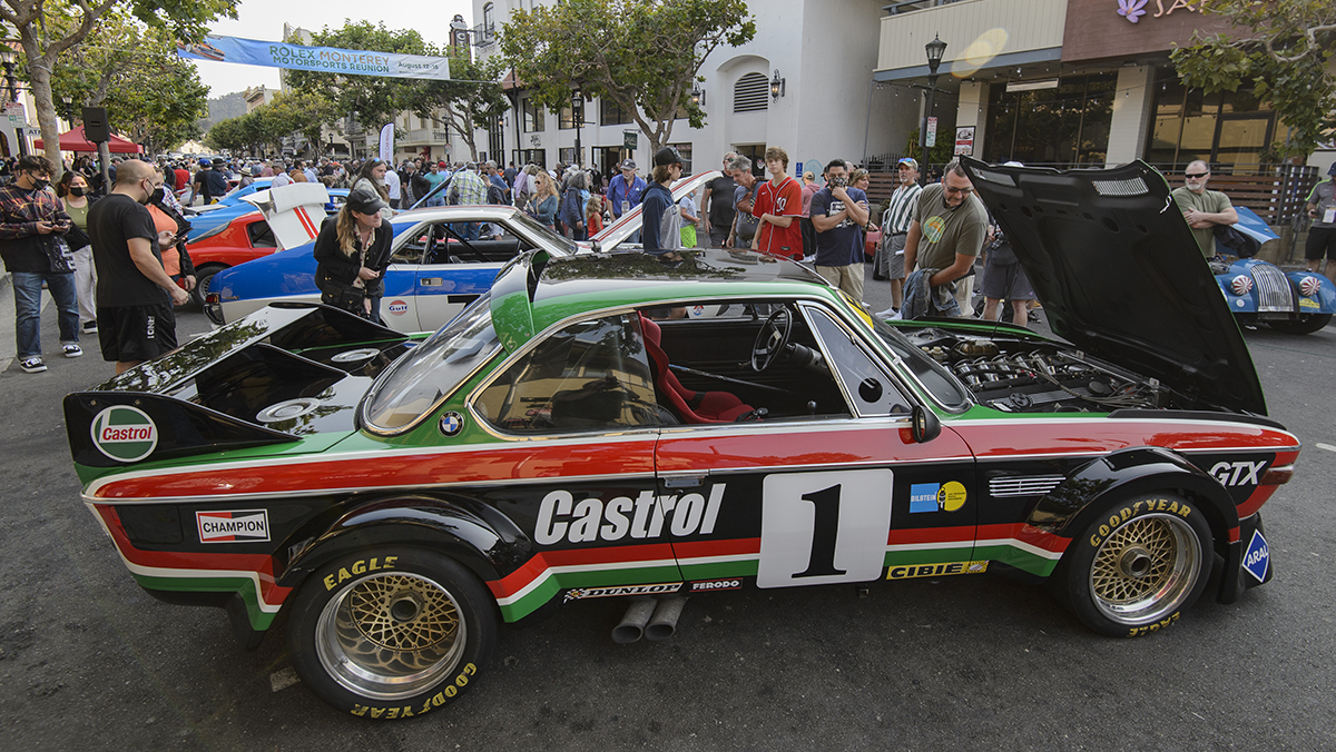 Classic race cars and crowds in street at Monterey Car Week