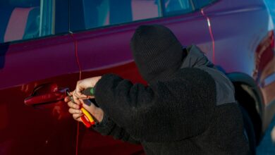 vehicle theft crook tampers with door on red car