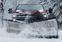Truck with snowplow attached to the front driving through the snow