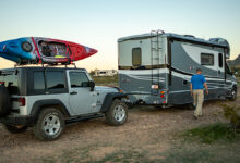 RV towing Jeep on dirt road