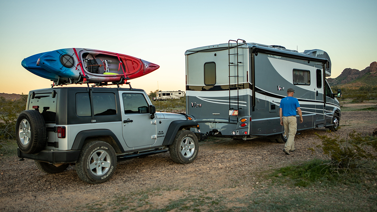 RV towing Jeep on dirt road