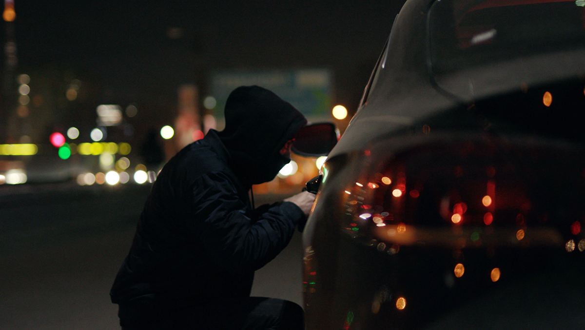 Person trying to break into car at night