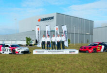 Team members and race cars in front of Hankook Tire building