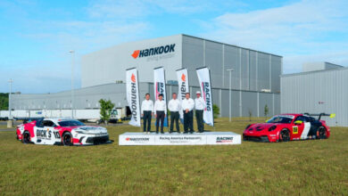 Team members and race cars in front of Hankook Tire building